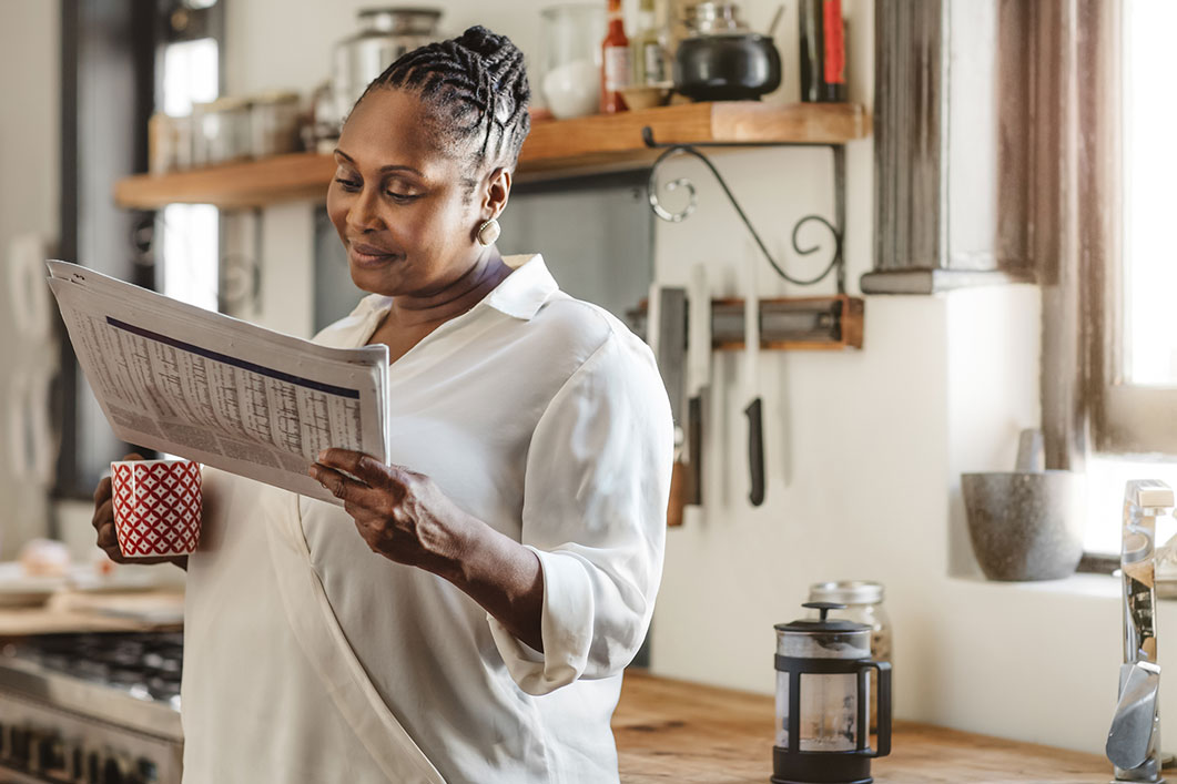 Woman reading paper drinking coffee